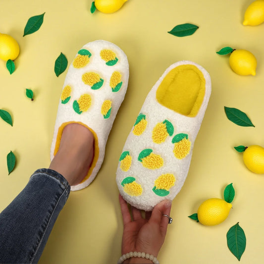 White slippers with lemon pattern on a yellow background with lemons and leaves.