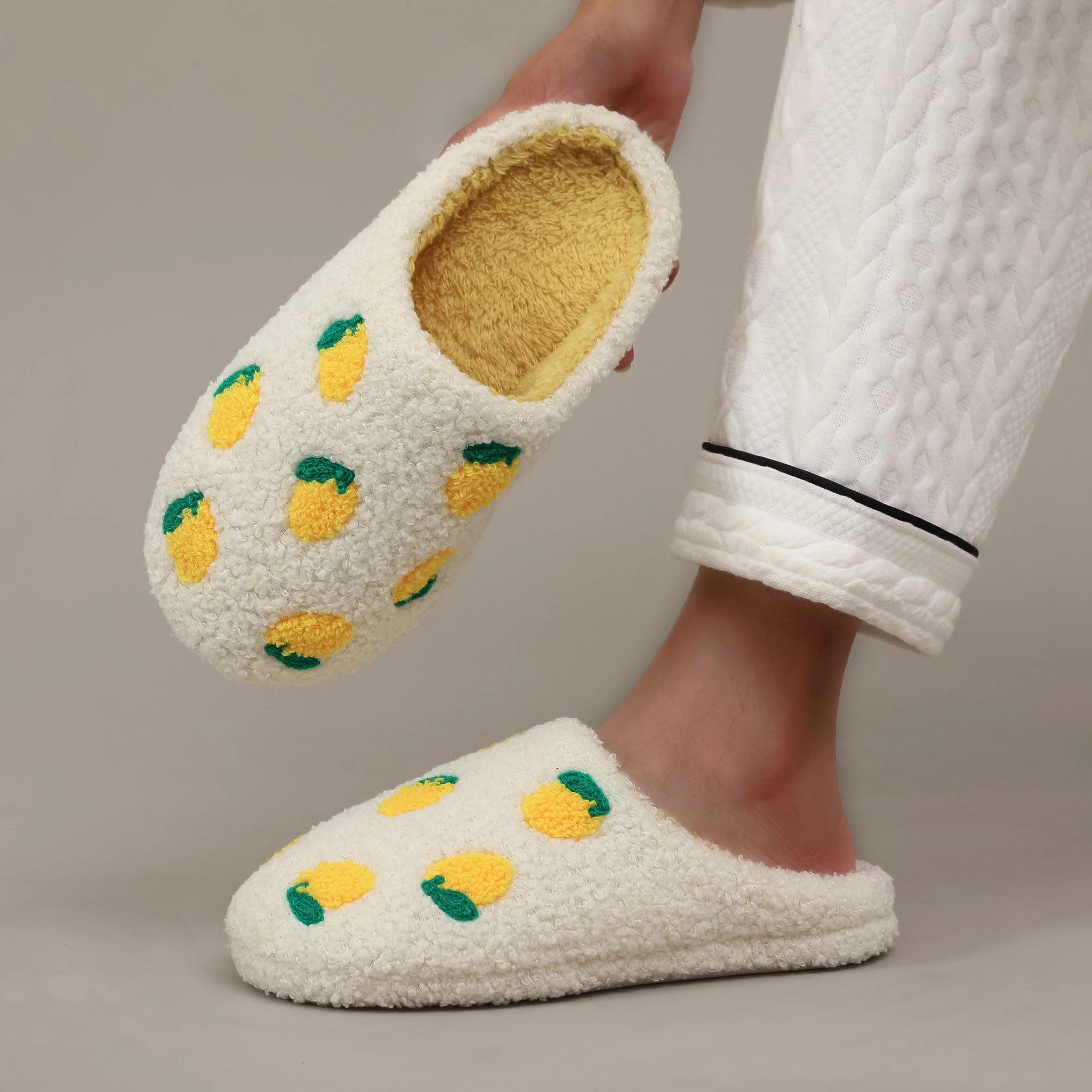 White slippers with lemon design worn by a person in a white robe.