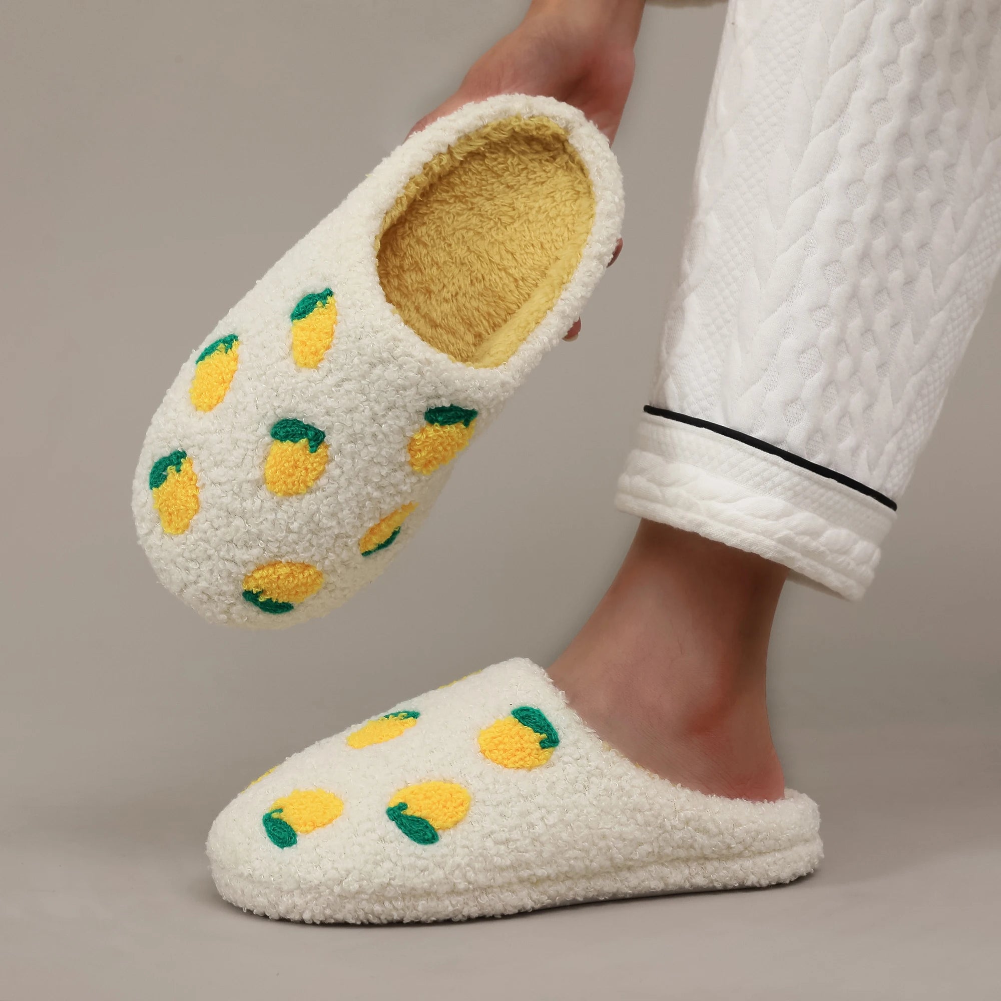 White slippers with lemon design worn by a person in a white robe.