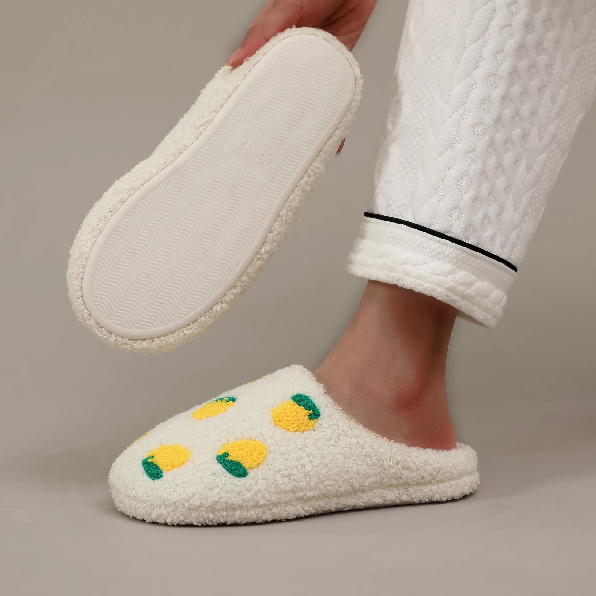 White slippers with yellow and green accents worn by a person in a white robe.